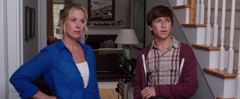 Movie still from “Vacation” (2015), directed by John Francis Daley – A woman and a boy standing next to each other in a living room; Medium shot, Over the shoulder angle