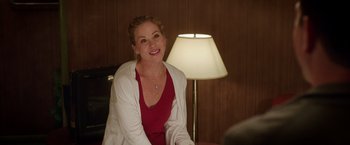 Movie still from “Vacation” (2015), directed by John Francis Daley – A woman sitting in front of a lamp in a dimly - lit room; Medium shot, Over the shoulder angle