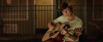 Movie still from “Vacation” (2015), directed by John Francis Daley – A young man is playing a guitar in the dark; Medium shot, Over the shoulder angle