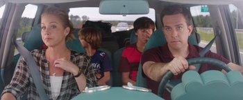 Movie still from “Vacation” (2015), directed by John Francis Daley – A man driving a car with a group of people in it; Medium shot, Over the shoulder angle