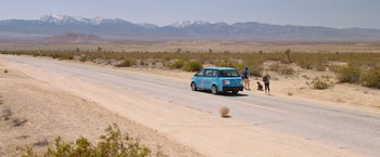 Movie still from “Vacation” (2015), directed by John Francis Daley – A blue van driving down a road with people standing on the side of the road; Extreme Wide shot, High angle