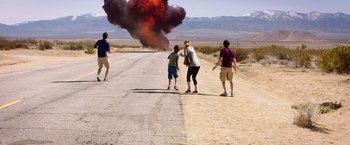 Movie still from “Vacation” (2015), directed by John Francis Daley – A group of people walking down a road with a black smoke cloud coming from it; Wide shot, High angle