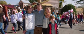 Movie still from “Vacation” (2015), directed by John Francis Daley – A family posing for a picture in front of some buildings; Medium shot, Over the shoulder angle