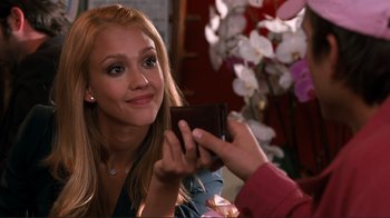 Movie still from “Valentine's Day” (2010), directed by Garry Marshall – A woman is holding a wallet and smiling; Close Up shot, Over the shoulder angle