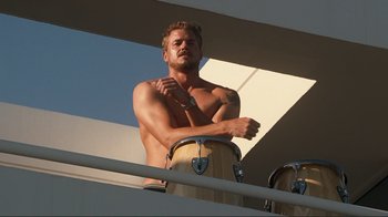 Movie still from “Valentine's Day” (2010), directed by Garry Marshall – A man standing on top of a balcony holding a drum; Medium shot, Low angle