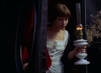 Movie still from “Valerie and Her Week of Wonders” (1970), directed by Jaromil Jires – A woman in a white dress looking at a lamp; Medium shot, High angle