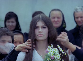 Movie still from “Valerie and Her Week of Wonders” (1970), directed by Jaromil Jires – A woman with long brown hair is holding a bouquet of flowers; Close Up shot, Over the shoulder angle