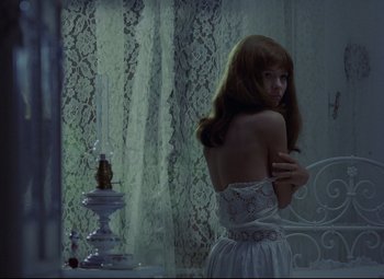 Movie still from “Valerie and Her Week of Wonders” (1970), directed by Jaromil Jires – A woman standing in front of a mirror in front of a window; Medium shot, High angle