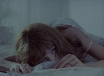 Movie still from “Valerie and Her Week of Wonders” (1970), directed by Jaromil Jires – A woman laying on a bed with her hands on her face; Medium shot, High angle