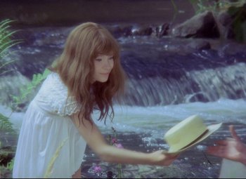 Movie still from “Valerie and Her Week of Wonders” (1970), directed by Jaromil Jires – A woman in a white dress holding a hat near a river; Medium shot, High angle