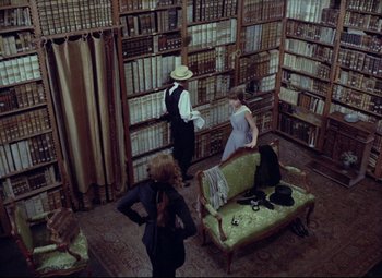 Movie still from “Valerie and Her Week of Wonders” (1970), directed by Jaromil Jires – A group of people standing in a room with books on the wall; Wide shot, High angle
