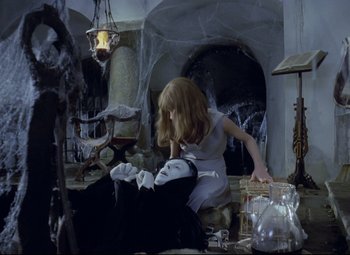 Movie still from “Valerie and Her Week of Wonders” (1970), directed by Jaromil Jires – A woman sitting on the floor next to a man in a suit; Wide shot, High angle