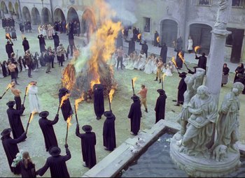 Movie still from “Valerie and Her Week of Wonders” (1970), directed by Jaromil Jires – A group of people standing in front of a fire in a courtyard; Extreme Wide shot, High angle