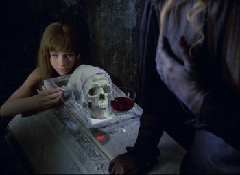 Movie still from “Valerie and Her Week of Wonders” (1970), directed by Jaromil Jires – A girl sitting in front of a human skull; Close Up shot, Over the shoulder angle