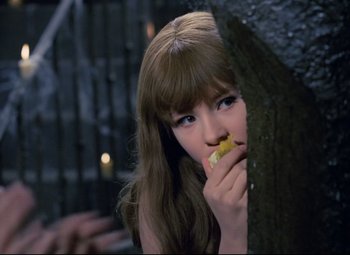Movie still from “Valerie and Her Week of Wonders” (1970), directed by Jaromil Jires – A woman eating a piece of food next to a tree; Close Up shot, Over the shoulder angle