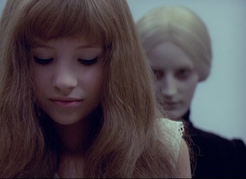 Movie still from “Valerie and Her Week of Wonders” (1970), directed by Jaromil Jires – A young girl with long brown hair is looking down at a doll; Close Up shot, Over the shoulder angle