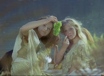 Movie still from “Valerie and Her Week of Wonders” (1970), directed by Jaromil Jires – Two young girls are holding a bunch of green grapes; Medium shot, Low angle