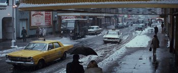 Movie still from “Valley of the Dolls” (1967), directed by Mark Robson – Two people are walking down a snowy street while cars are driving down the street; Extreme Wide shot, High angle