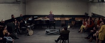 Movie still from “Valley of the Dolls” (1967), directed by Mark Robson – A woman standing in front of a man playing a piano; Wide shot, High angle