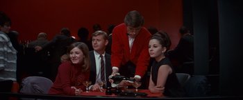 Movie still from “Valley of the Dolls” (1967), directed by Mark Robson – A group of people sitting at a table with wine glasses; Medium shot, High angle