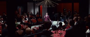 Movie still from “Valley of the Dolls” (1967), directed by Mark Robson – A man in a purple suit stands in front of an audience; Extreme Wide shot, High angle