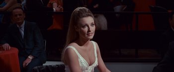 Movie still from “Valley of the Dolls” (1967), directed by Mark Robson – A woman in a white dress sitting in front of a camera; Close Up shot, Low angle