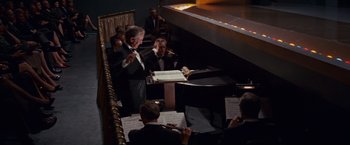 Movie still from “Valley of the Dolls” (1967), directed by Mark Robson – A man in a black suit is playing a musical instrument; Wide shot, High angle