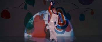 Movie still from “Valley of the Dolls” (1967), directed by Mark Robson – A woman in a long dress and high heel shoes; Wide shot, Low angle