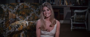 Movie still from “Valley of the Dolls” (1967), directed by Mark Robson – A woman in a white dress sitting in a living room; Medium shot, Over the shoulder angle
