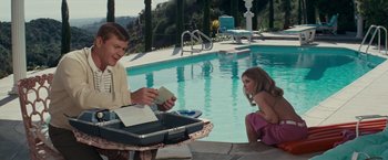 Movie still from “Valley of the Dolls” (1967), directed by Mark Robson – A man and a little girl sitting by a swimming pool; Medium shot, High angle
