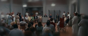 Movie still from “Valley of the Dolls” (1967), directed by Mark Robson – A group of people sitting in a room with chairs; Wide shot, High angle