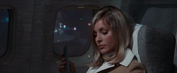 Movie still from “Valley of the Dolls” (1967), directed by Mark Robson – A beautiful young woman holding a book while sitting on a plane; Close Up shot, Low angle