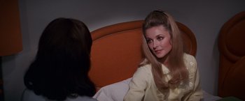 Movie still from “Valley of the Dolls” (1967), directed by Mark Robson – A woman sitting on top of a bed next to another woman; Medium shot, Over the shoulder angle