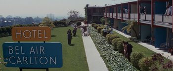 Movie still from “Valley of the Dolls” (1967), directed by Mark Robson – A group of people standing on a lush green lawn; Extreme Wide shot, High angle