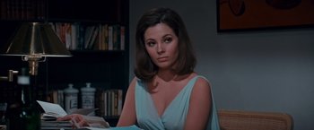 Movie still from “Valley of the Dolls” (1967), directed by Mark Robson – A woman in a blue dress sitting in front of a book shelf; Close Up shot, High angle