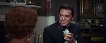 Movie still from “Valley of the Dolls” (1967), directed by Mark Robson – A man in a tuxedo is holding a glass of wine; Close Up shot, Over the shoulder angle