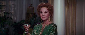Movie still from “Valley of the Dolls” (1967), directed by Mark Robson – An older woman holding a wine glass in a green dress; Close Up shot, Over the shoulder angle