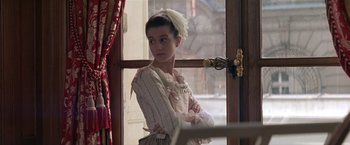 Movie still from “Valmont” (1989), directed by Milos Forman – A woman standing in front of a window with her arms crossed; Medium shot, Over the shoulder angle