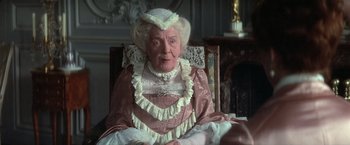 Movie still from “Valmont” (1989), directed by Milos Forman – An older woman in a pink dress sitting in a chair; Close Up shot, High angle