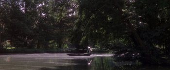 Movie still from “Valmont” (1989), directed by Milos Forman – A man in a boat on a body of water near trees; Extreme Wide shot, High angle