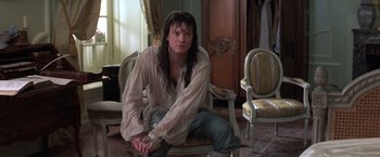 Movie still from “Valmont” (1989), directed by Milos Forman – A man sitting on a chair in a living room; Medium shot, Over the shoulder angle