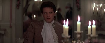 Movie still from “Valmont” (1989), directed by Milos Forman – A man with a white scarf around his neck and a lit candle in the background; Close Up shot, Over the shoulder angle