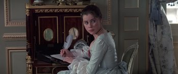 Movie still from “Valmont” (1989), directed by Milos Forman – A woman in a white dress writing on a paper; Medium shot, Over the shoulder angle