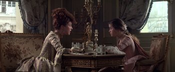 Movie still from “Valmont” (1989), directed by Milos Forman – Two women sitting at a table talking to each other; Medium shot, Over the shoulder angle