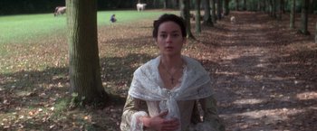 Movie still from “Valmont” (1989), directed by Milos Forman – A woman in a white dress standing next to a tree; Medium shot, High angle