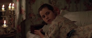 Movie still from “Valmont” (1989), directed by Milos Forman – A young girl sitting on a bed looking at the camera; Close Up shot, Over the shoulder angle