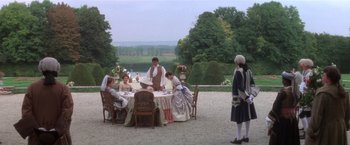 Movie still from “Valmont” (1989), directed by Milos Forman – A group of people sitting at a table in front of a river; Wide shot, High angle