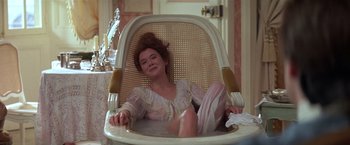 Movie still from “Valmont” (1989), directed by Milos Forman – A woman sitting in a chair with her legs crossed; Medium shot, High angle