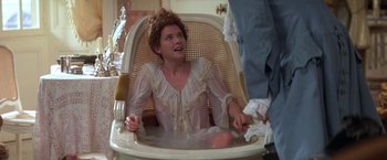 Movie still from “Valmont” (1989), directed by Milos Forman – A woman sitting in a wicker chair in a bathroom; Medium shot, High angle