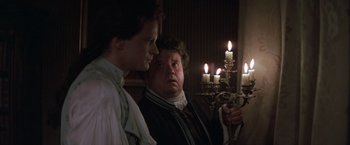 Movie still from “Valmont” (1989), directed by Milos Forman – Two men standing next to each other in front of candles; Medium shot, Over the shoulder angle